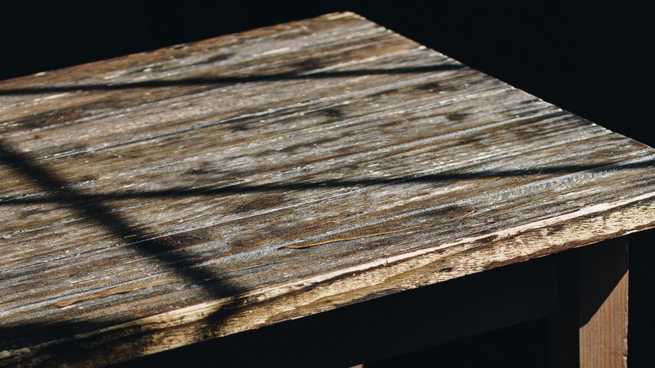 Stara drvena ploča stola sa istrošenom i ispucalom površinom.